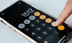 Finanzierungsrechner Teaser - iPhone Calculator App offen und ein Finger tippt auf das geteilt Zeichen